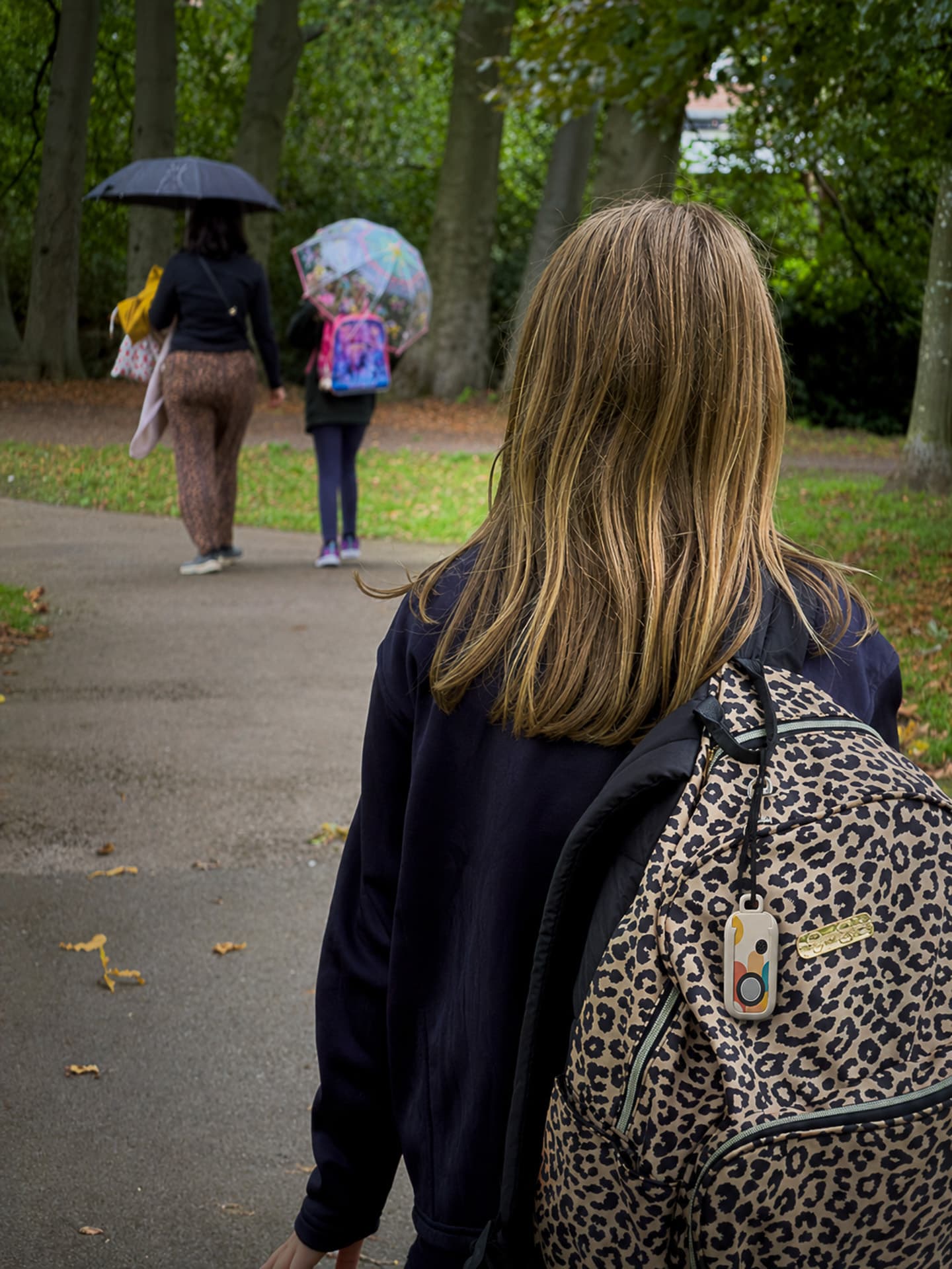 A girl with a backpack walking through a school side gate on her own in the morning.